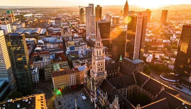 Golden-hour skyline with gothic town hall tower rising above historic plaza and skyscrapers
