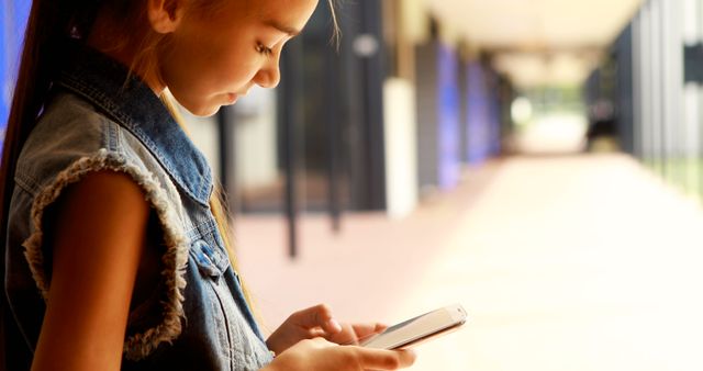 Young Girl Engaged with Smartphone in School Corridor - Download Free Stock Images Pikwizard.com