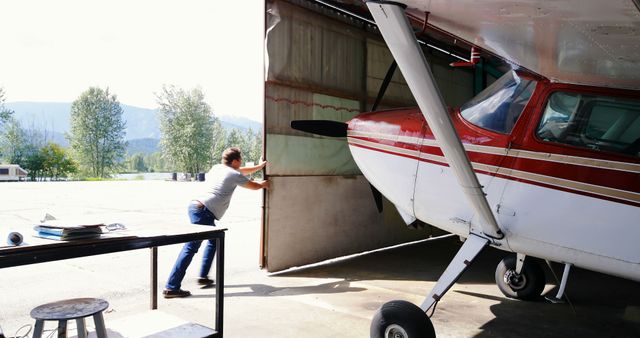Man Pushing Light Airplane into Hangar - Download Free Stock Images Pikwizard.com