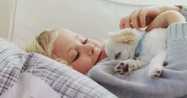 A young Caucasian girl enjoys a tender moment with her small puppy, with copy space. Their affectionate interaction showcases the special bond between children and their pets.