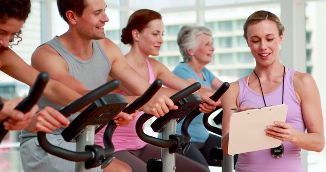 Group Spinning Class with Instructor Taking Notes at Fitness Center - Download Free Stock Images Pikwizard.com