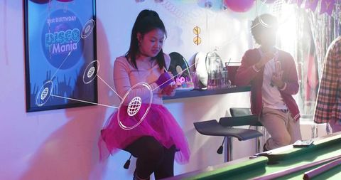Young woman sitting in pink tulle skirt checking smartphone at home disco party bar