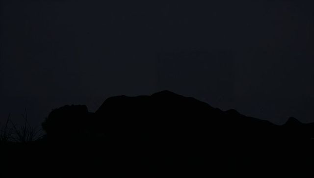 Lying male silhouette on grassy hillside at night conveying solitude and mystery