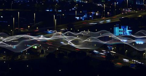 Streaming dotted wave floating above night highway with traffic light trails and neon cityscape