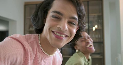 Diverse friends laughing and leaning toward camera with pearl necklace and gold earrings