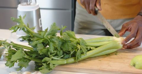 Man chopping celery on wooden cutting board closeup healthy cooking prep kitchen counter