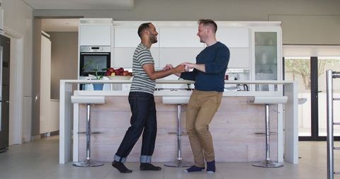 Multicultural couple dancing at home preparing meal