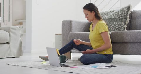 Focused Woman Working from Home with Laptop and Documents