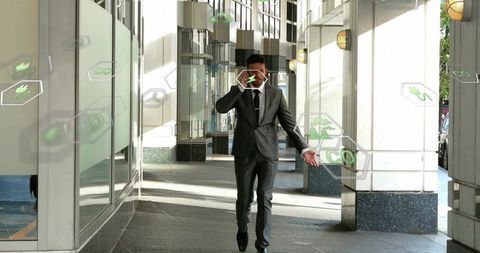 Executive walking while using smartphone with ar hexagonal icons in modern glass arcade