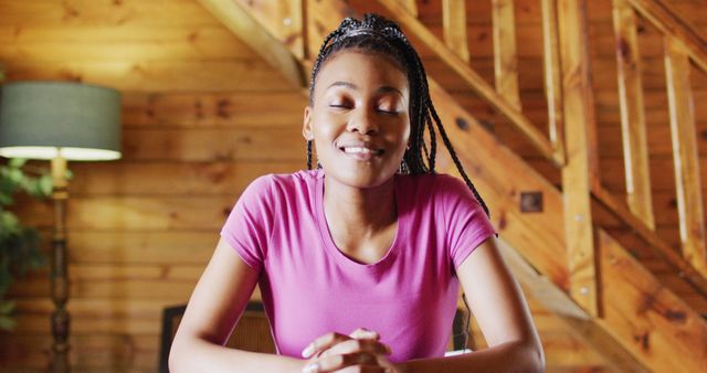 Young woman with braided hair enjoying a moment of relaxation in a cozy wooden interior. Perfect for lifestyle, home, relaxation, happiness, and wellness-themed uses such as blog posts, social media content, and advertisements promoting a serene lifestyle.