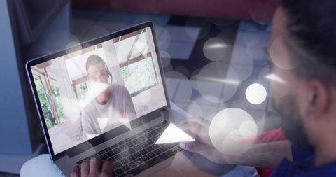 Man joining video call on laptop using trackpad and headset, home workspace in daylight