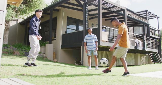 Friends are spending time together playing soccer on a sunny day in a backyard. Setting is a modern house with a deck. Ideal for themes of friendship, outdoor recreation, summer activities, and youth sports.