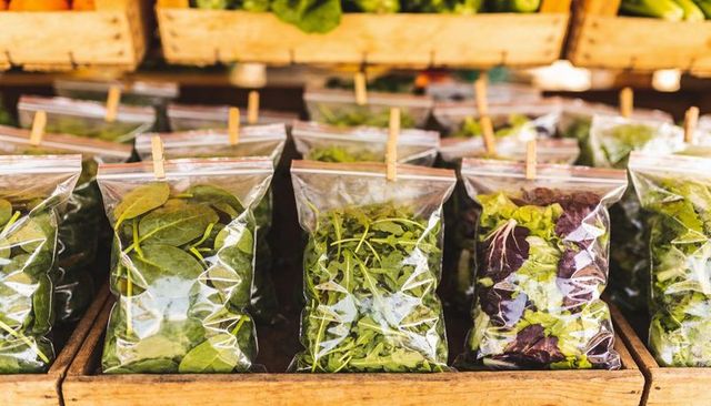 Displaying packaged salad greens in clear bags on rustic wooden market crates