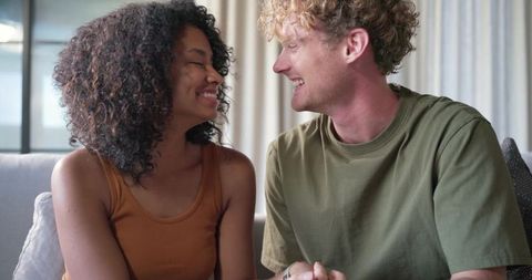 Couple sharing warm moment on light-gray sofa holding hands and smiling