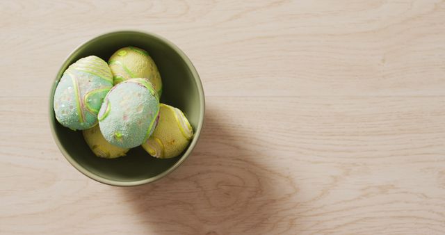 Image of decorated colorful easter eggs in bowl on a wooden surface. seasonal easter traditional sweet treats.
