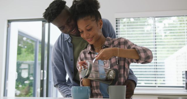 Image of happy african american couple preparing coffee and embracing at home - Download Free Stock Photos Pikwizard.com