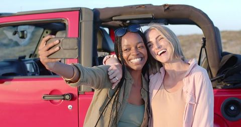 Joyful friends taking selfie on scenic road trip