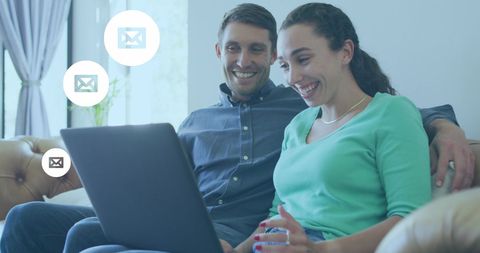 Smiling couple engaging with emails on laptop
