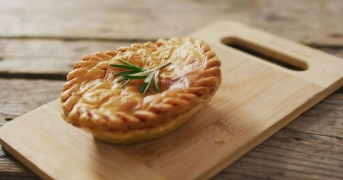 Homemade savory pie with flaky crust on wooden board