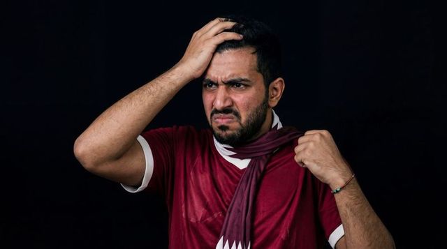 Frustrated sports fan gripping head and pulling maroon scarf in tense emotional portrait