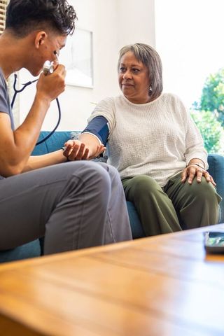 Nurse Checking Blood Pressure of Senior Woman at Home with Care and Comfort