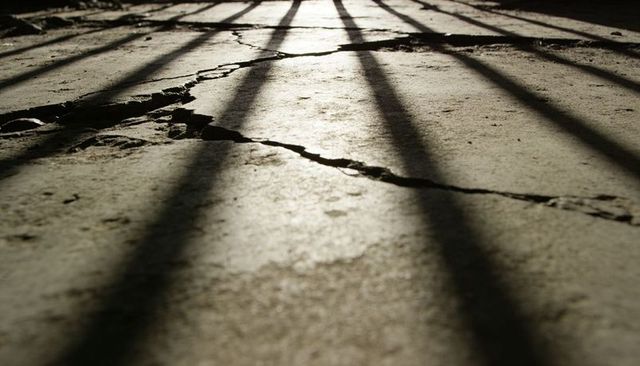 Cracked concrete floor with long parallel shadow bars and diagonal fissure texture