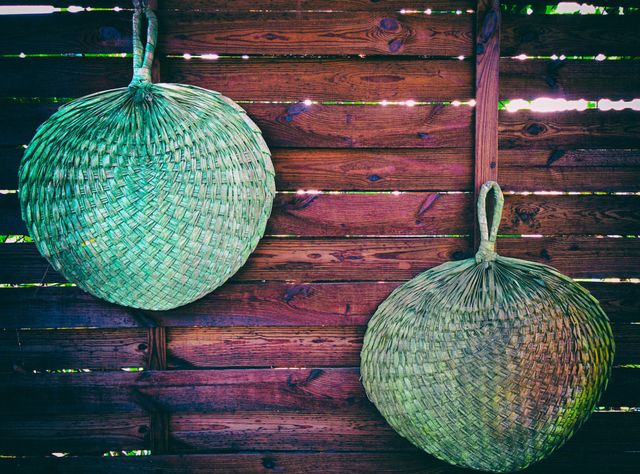 Two traditional woven baskets hanging on a rustic wooden fence. Baskets made from natural materials like straw. Ideal for illustrating concepts of handcrafted items, rural living, cottage decor, or eco-friendly products. Suitable for websites about handicrafts, nature-friendly decor, or country-style interiors and outdoor spaces.