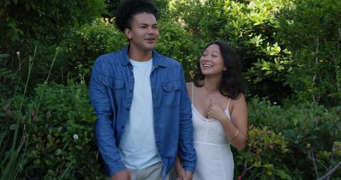 Couple Holding Hands and Laughing in Lush Garden