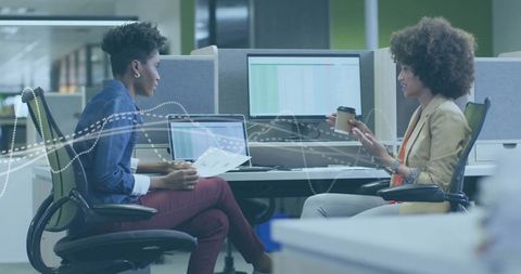 Businesswomen discussing report in modern office environment