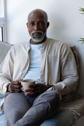 Serene mature african man enjoying morning coffee on sunlit window seat