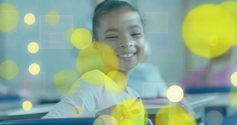 Smiling schoolgirl holding pencil and turning in classroom with warm bokeh lights