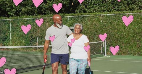 Senior couple embracing on tennis court with floating hearts graphic