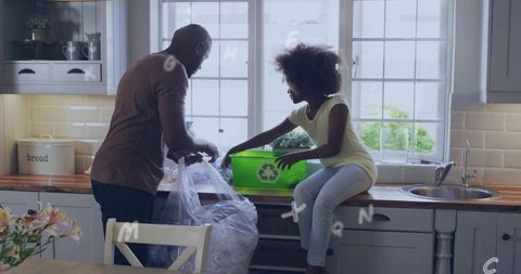 Father and daughter sorting recyclables in sunlit kitchen with bright green recycling bin