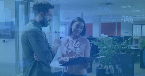 Coworkers reviewing document in modern open-plan office