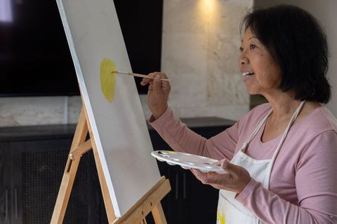 Middle Aged Woman Painting a Yellow Circle on a Canvas Art Inspiration