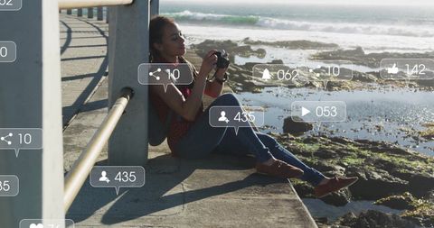 Woman Sitting by Ocean Taking Photos with Social Media Icons Overlay - Download Free Stock Images Pikwizard.com