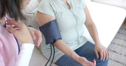 Healthcare Professional Checking Senior Woman's Blood Pressure at Home