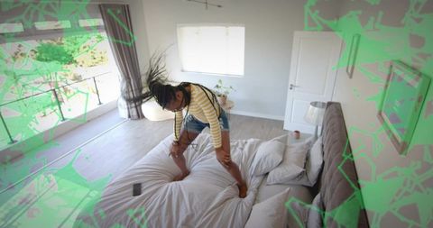 Woman balancing joyfully on bed in cozy bedroom setting