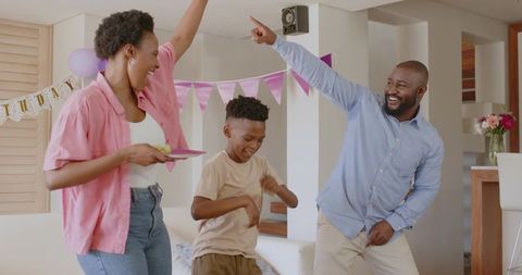 African American Family Dancing Joyfully at Home Birthday Party with Balloons, Bunting