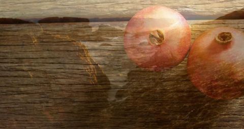 Ripe Pomegranates with Coastal Sunset on Wooden Surface