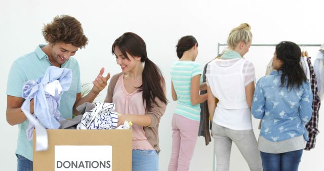 Team of happy workers going through donation box of clothes in their workplace