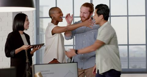 Diverse Business Team Celebrating Success with Smiles and Joyful Hugs