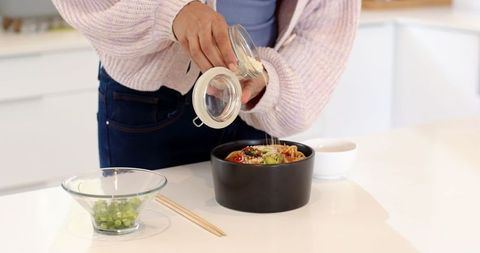 Preparing healthy salad with seeds in modern kitchen