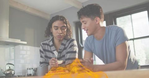 Holding apple slice while talking in sunlit kitchen with orange digital mesh overlay