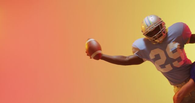 Image of an American football player catching a ball with an arm extended against a vibrant gradient background. Suitable for use in sports promotions, athletic campaigns, team spirit advertisements, and fitness or athletic event materials.