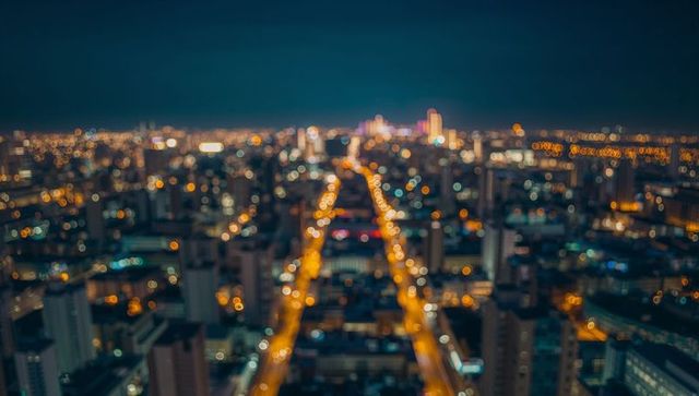 Blurred nighttime city skyline with illuminated streets and towers