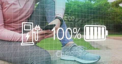 Woman sitting on park curb holding smartphone with wearable showing 100% battery charging