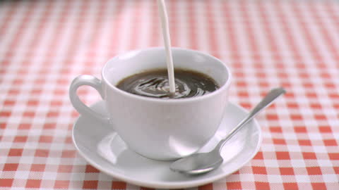 Slow Motion Milk Pours into Cup of Coffee With Swirling Effect