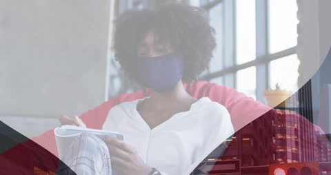 Woman Wearing Mask Reviewing Notes Amidst Overlayed Data Graphics