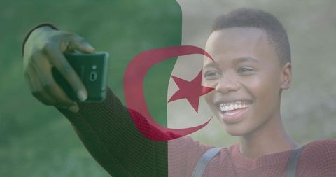 Young woman taking selfie with algeria flag overlay, left-handed smartphone portrait